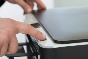 Businessman's Finger Pressing Button Of Photocopy Machine