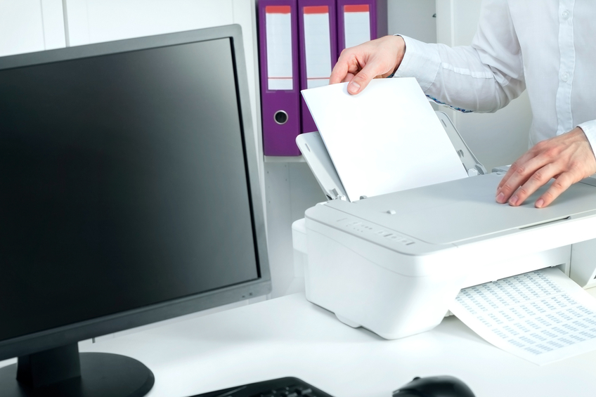 Man puts stack of paper into white printer