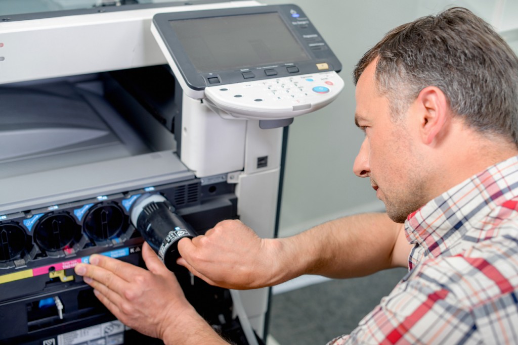 Man adding new toner cartridge to printer