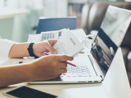 Man holding CV in front of laptop